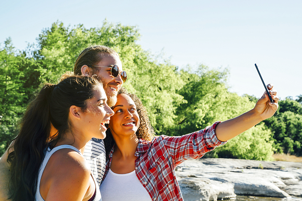 Friends posing for cell phone selfie outdoors