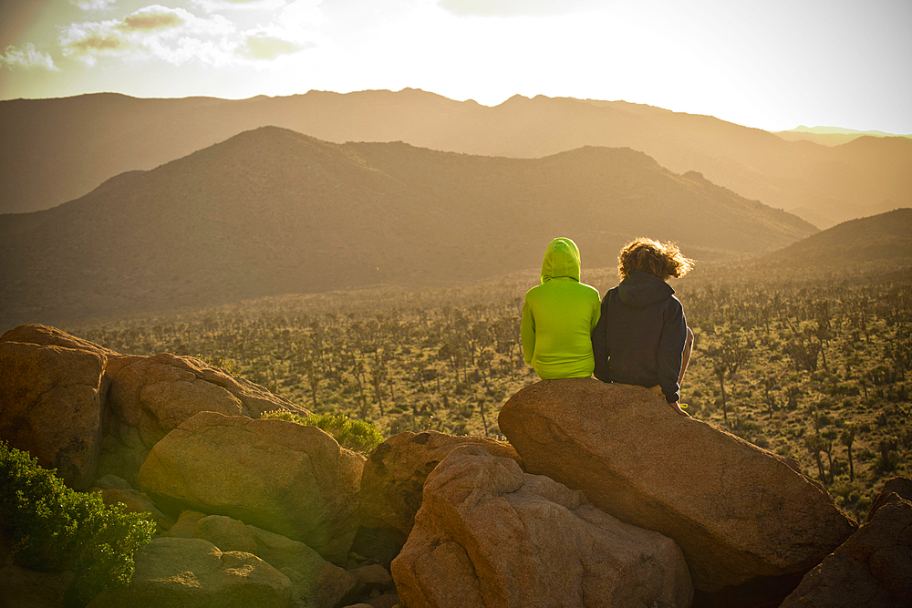 Boys sitting on rock admiring desert landscape