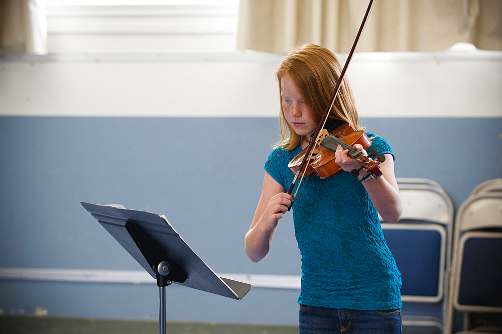 Caucasian girl practicing violin