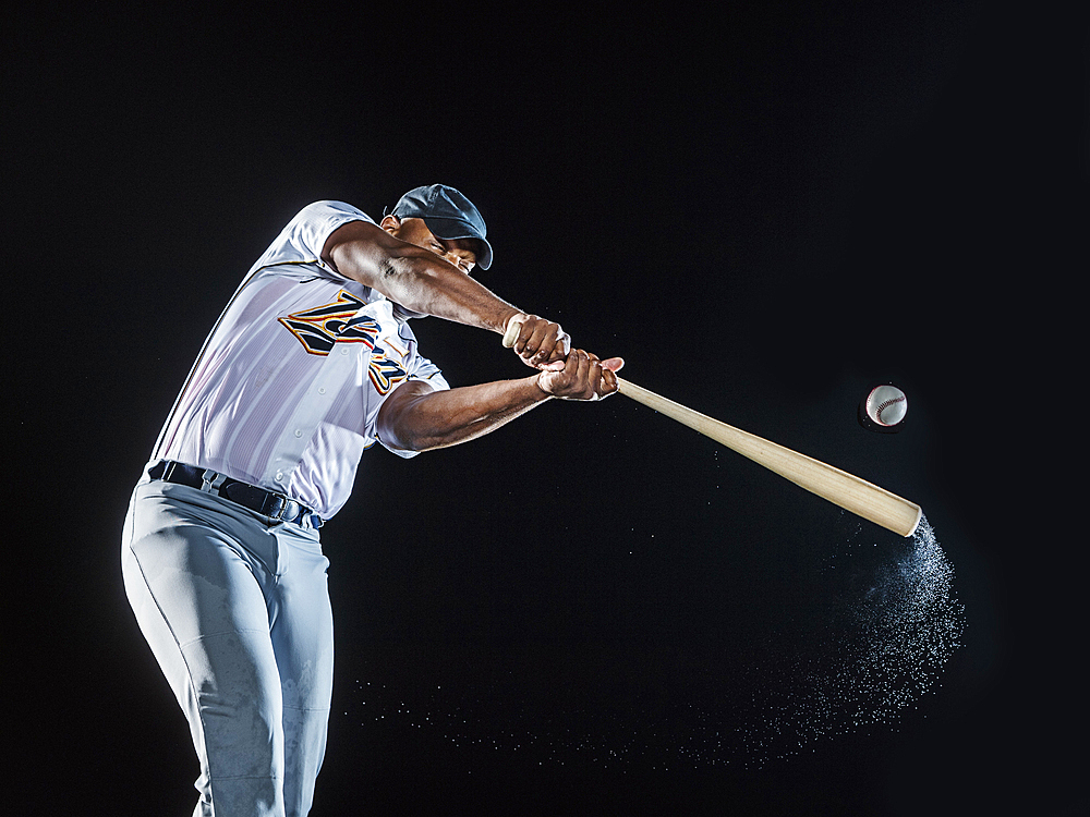 Water splashing from swinging bat of black baseball player