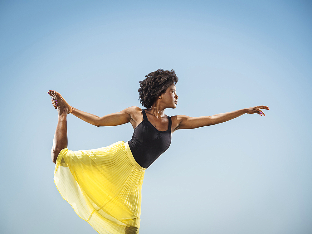 Black woman standing on one leg holding foot