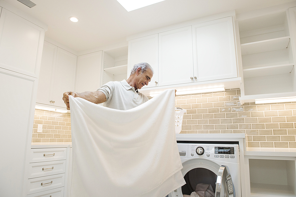 Caucasian man folding towel in modern laundry room