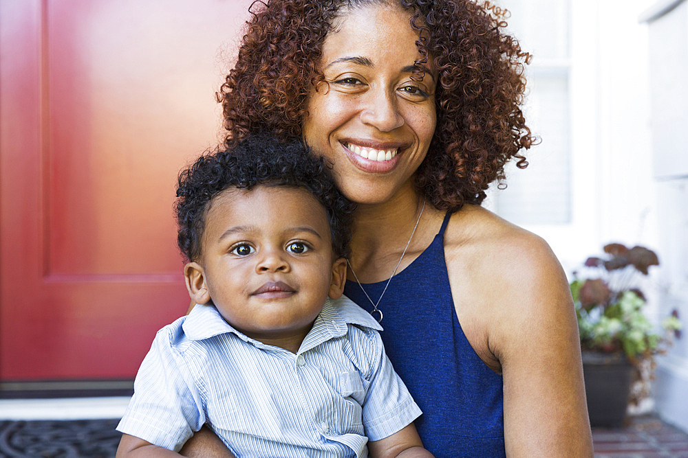 Smiling mixed race mother and baby son sitting on front stoop