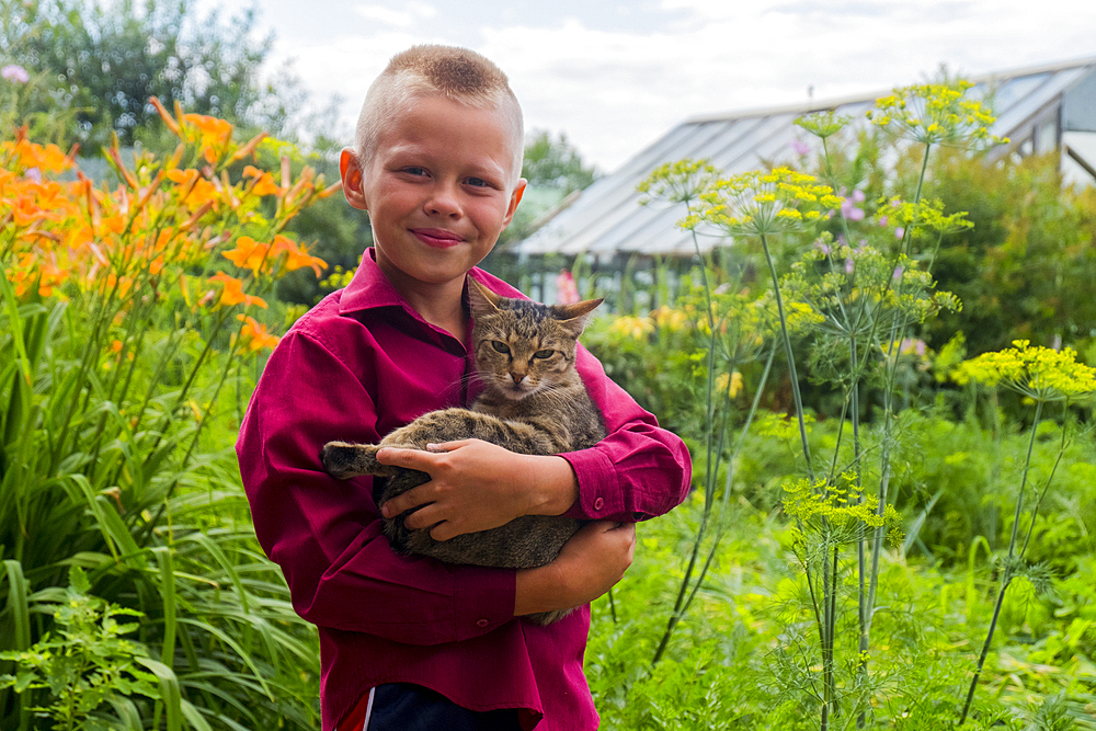 Caucasian boy holding cat on farm