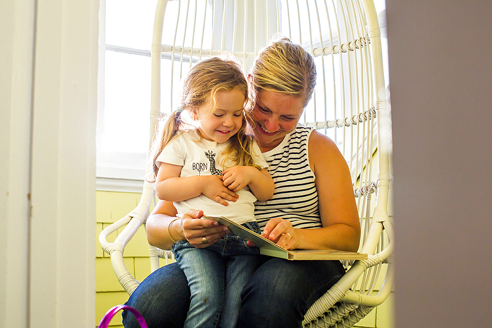 Caucasian mother reading book to daughter on lap