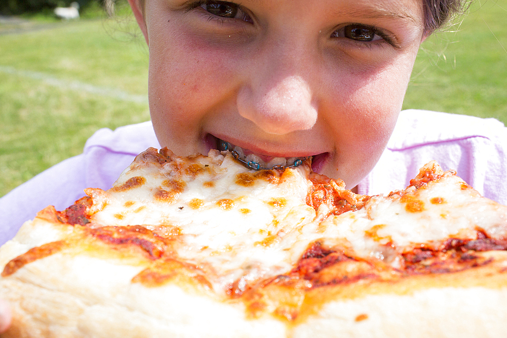 Close up of Caucasian girl with braces biting pizza