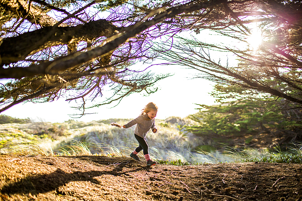 Caucasian girl running under tree branches