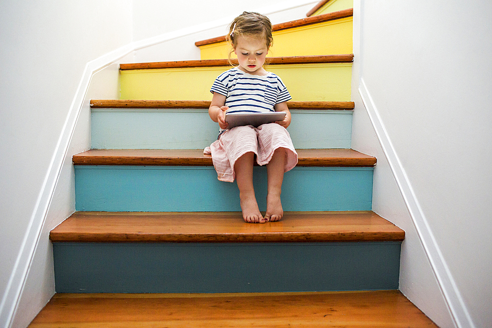 Caucasian girl using digital tablet on staircase