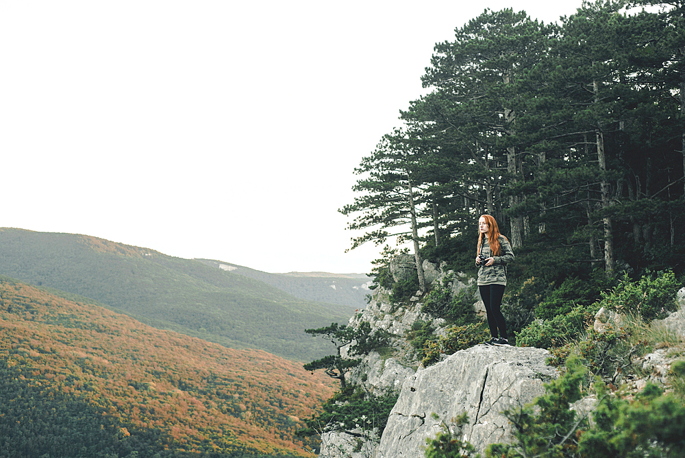 Caucasian woman standing on rock admiring scenic view of landscape