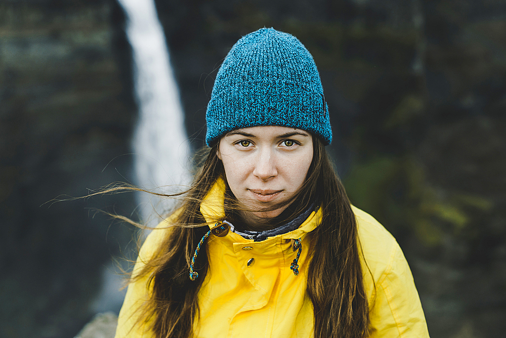 Wind blowing hair of Caucasian woman near waterfall