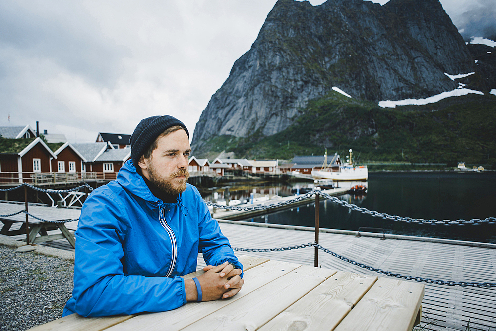 Pensive Caucasian man sitting at table at waterfront