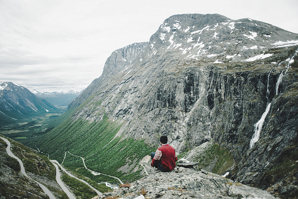 Caucasian man sitting on rock admiring scenic view of valley