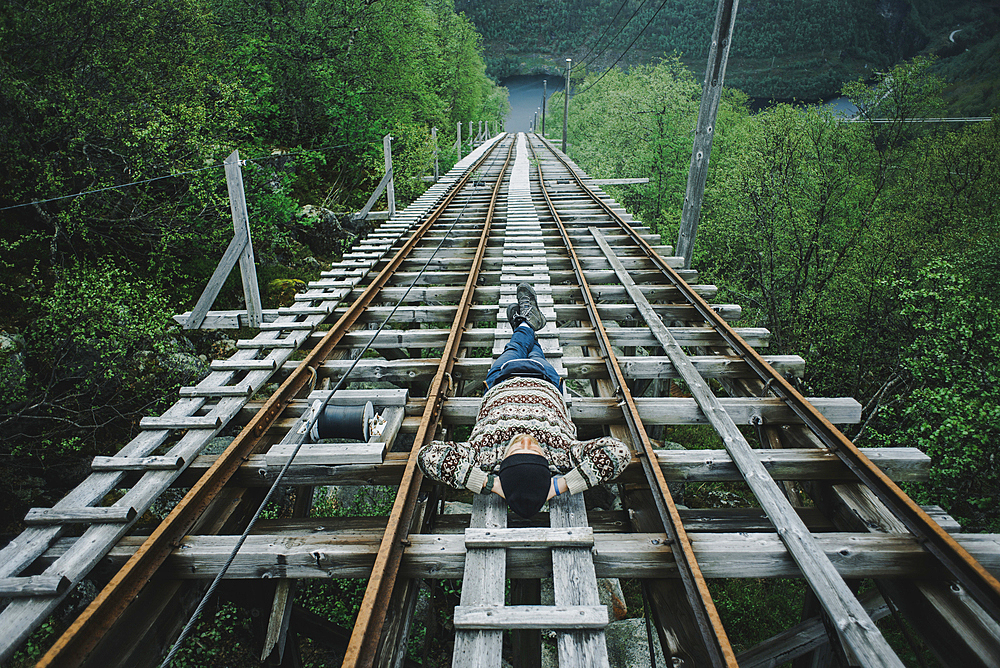 Caucasian man laying on train tracks