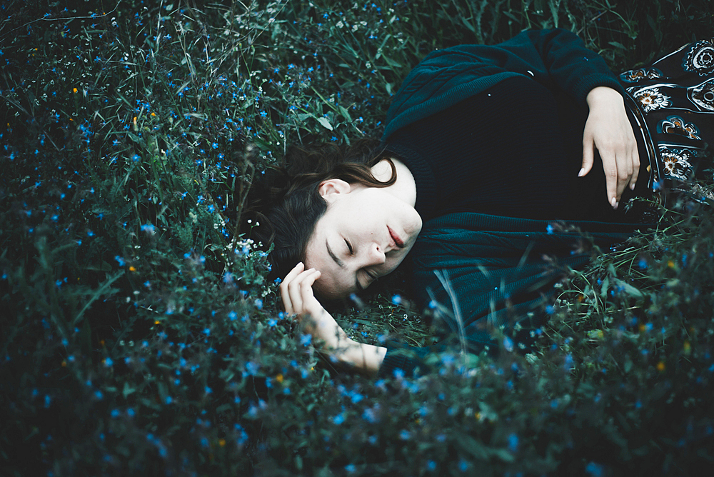 Caucasian woman laying in field of wildflowers