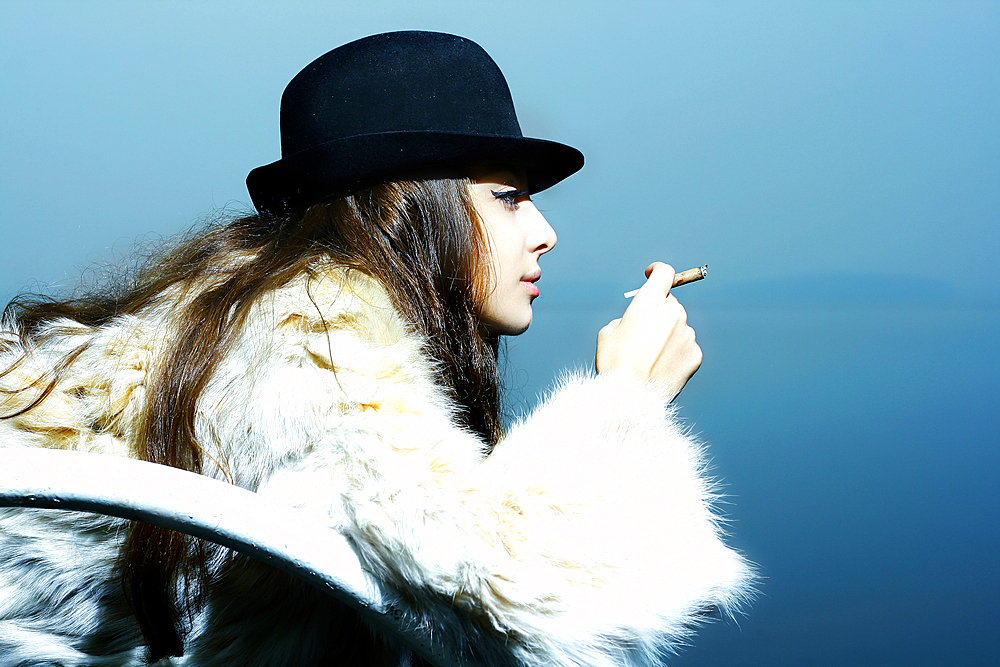 Portrait of glamorous woman wearing fur coat smoking cigarette