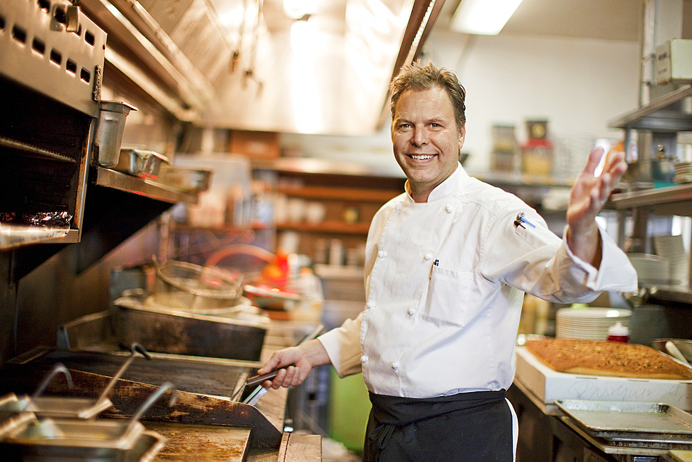 Portrait of Caucasian chef waving in restaurant kitchen