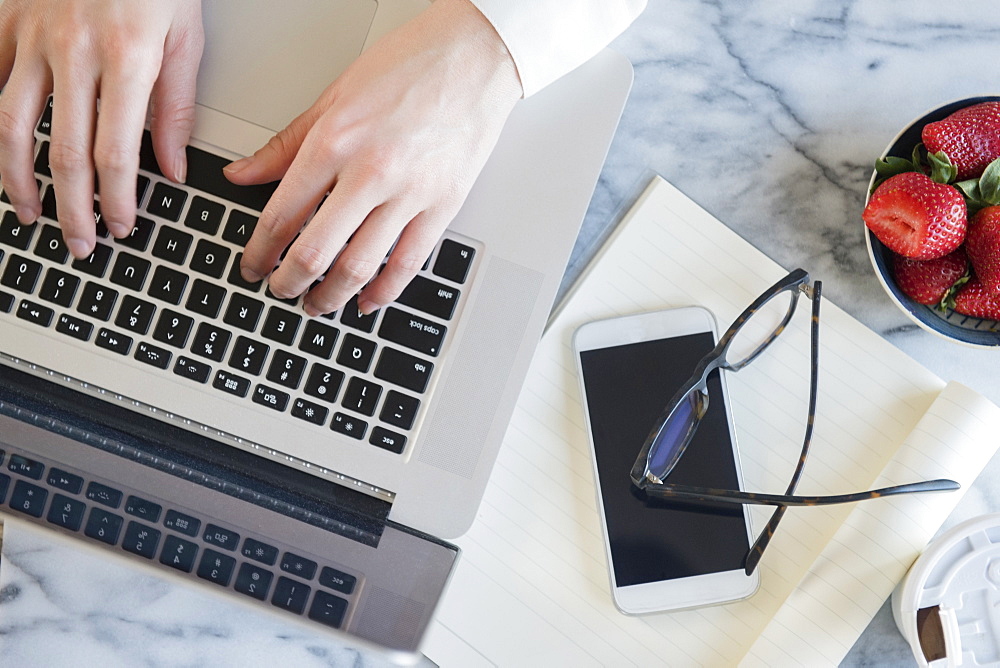 Hands of Caucasian woman typing on laptop