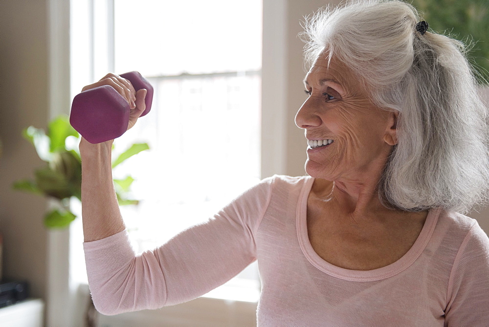 Smiling older woman lifting weights