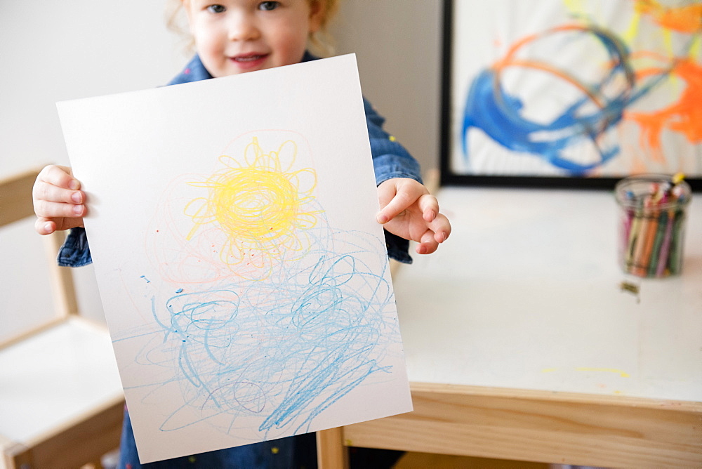 Caucasian girl showing drawing on paper