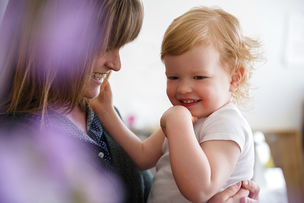 Caucasian mother holding laughing daughter