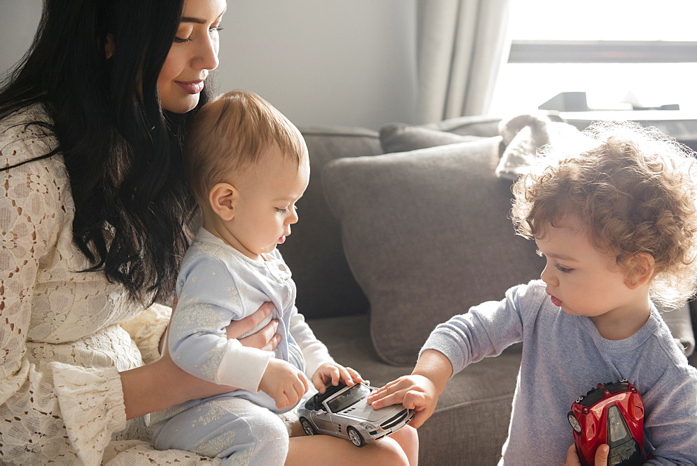 Caucasian mother watching sons playing with toy cars