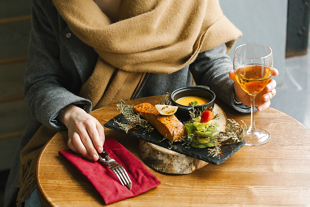 Woman eating fish with white wine