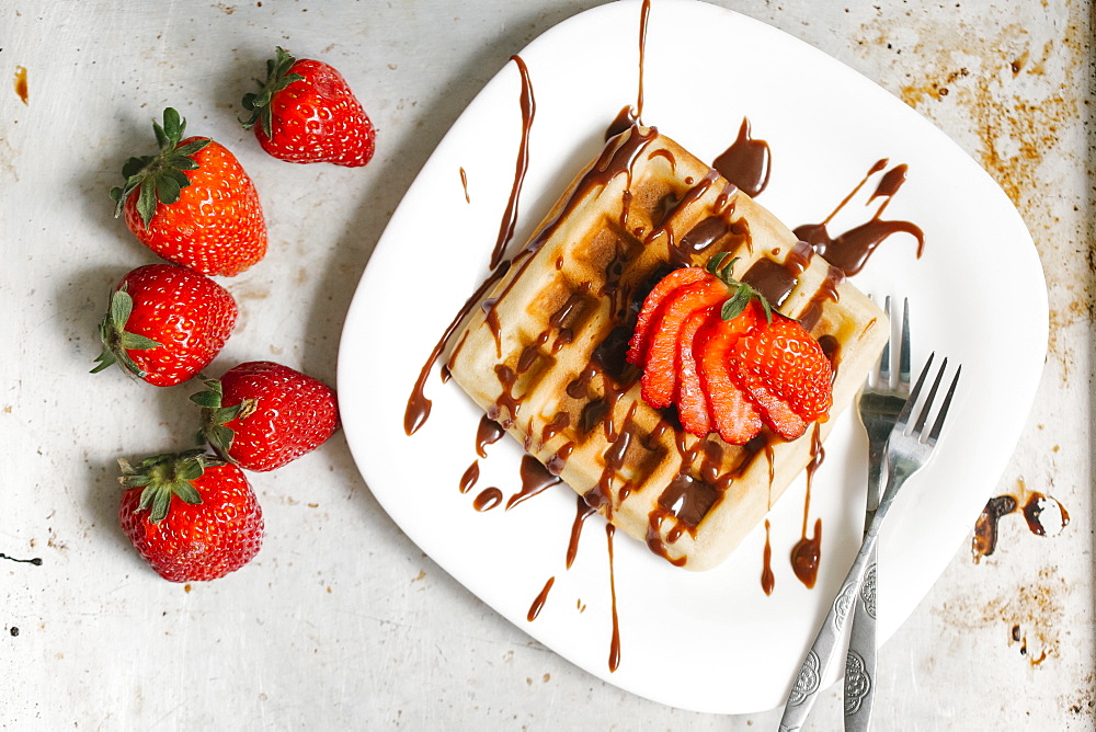 Sliced strawberries and chocolate syrup on waffle