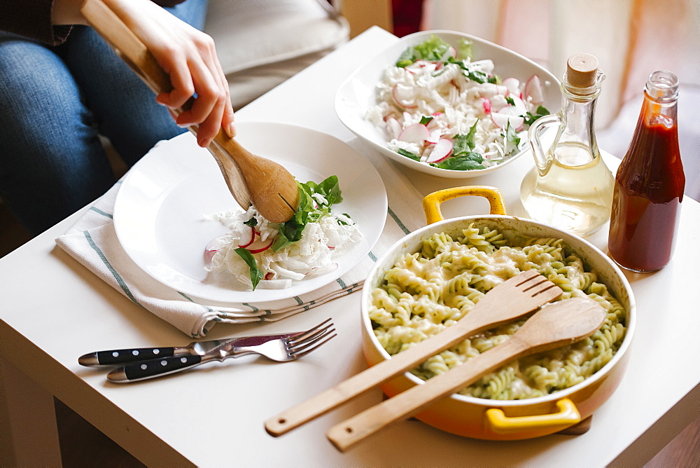 Woman serving salad with wooden tongs