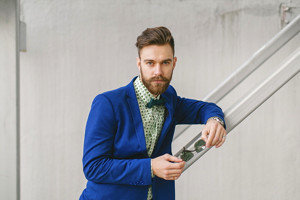 Stylish Middle Eastern man with beard holding sunglasses