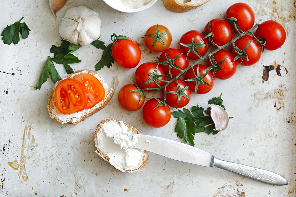 Tomatoes on vine near cream cheese and bread