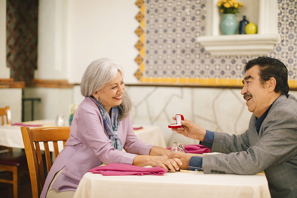 Older man proposing marriage to woman in restaurant