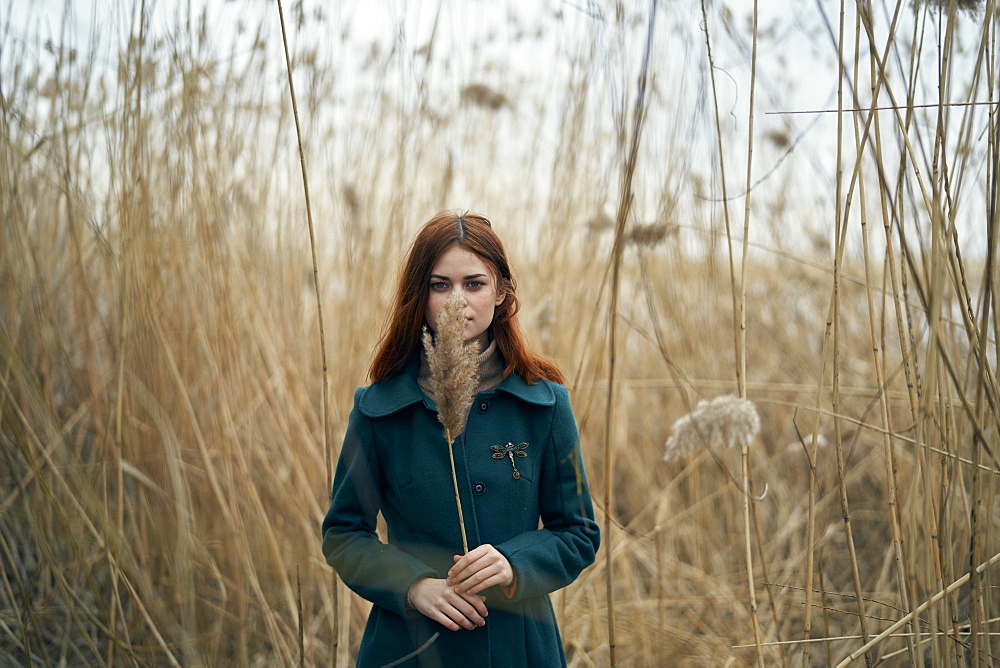 Caucasian woman standing in field holding stalk of grass