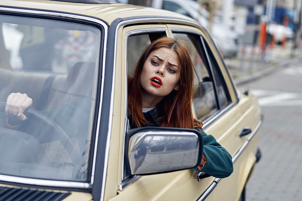 Frustrated Caucasian woman leaning on door driving car