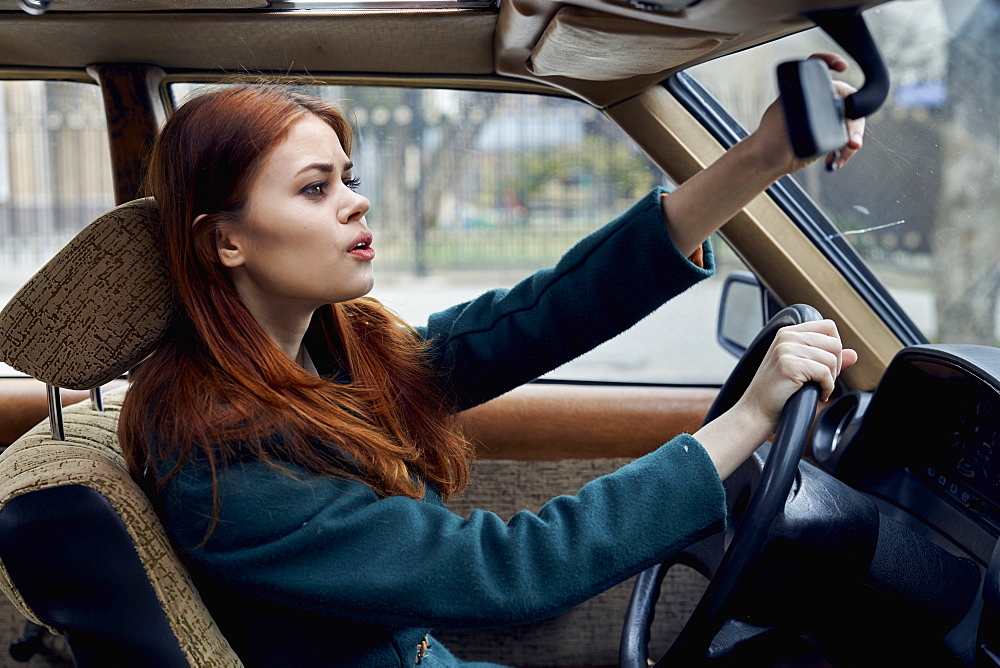 Caucasian woman driving car adjusting mirror