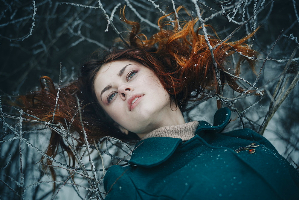 Serious Caucasian woman laying on icy branches