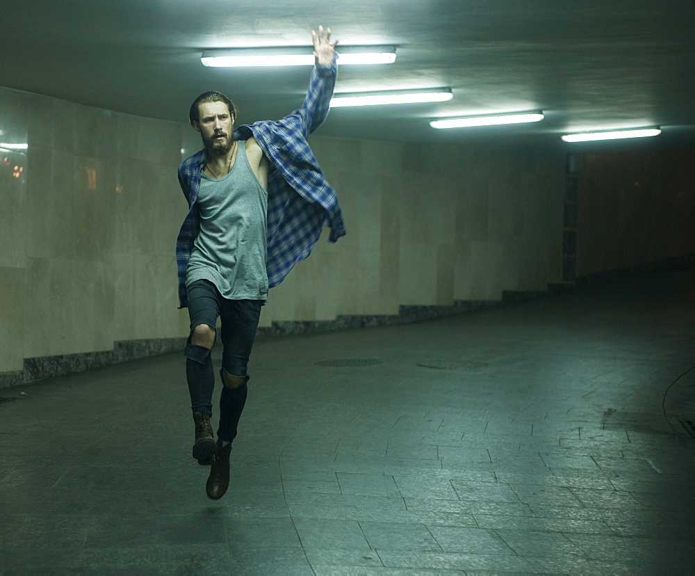 Carefree Caucasian man skipping in tunnel