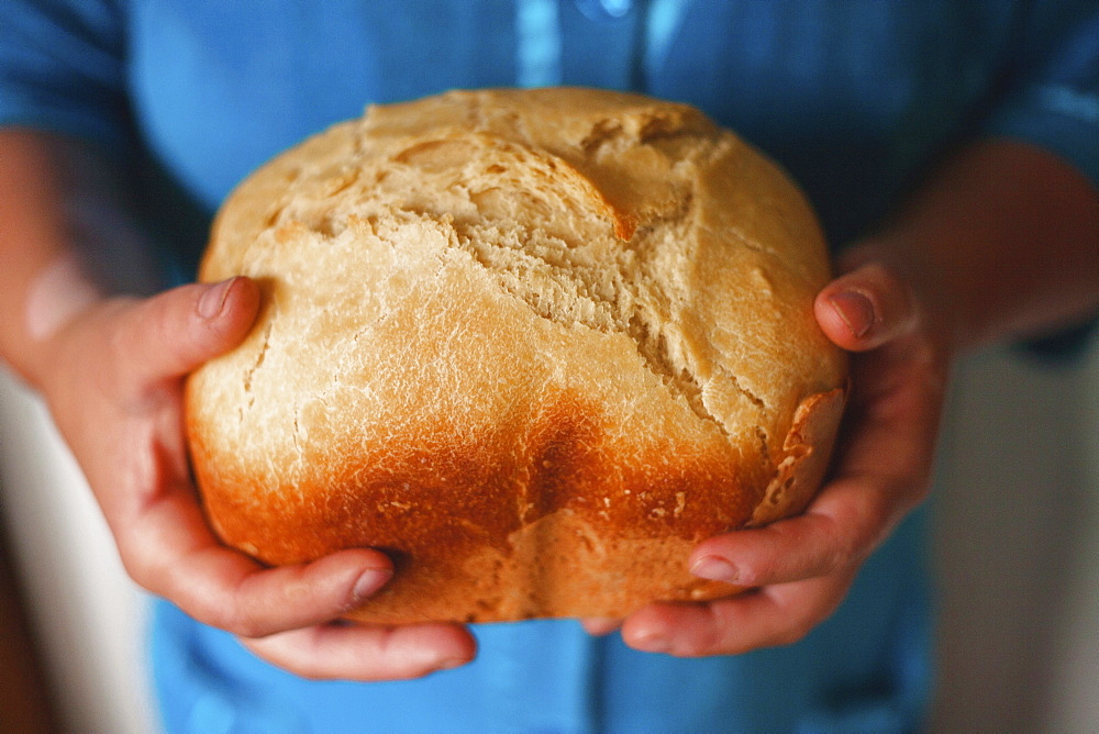 Hands holding loaf of bread