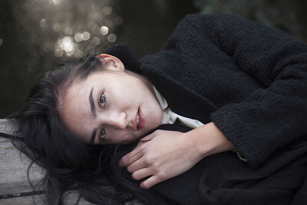 Portrait of serious Caucasian woman laying on wood