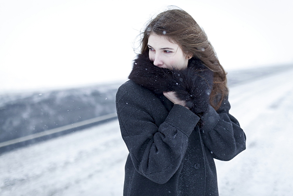 Caucasian woman nestling in fur collar outdoors in winter