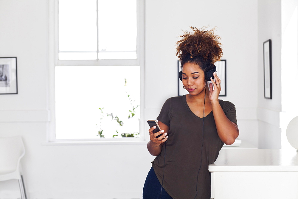 Mixed race woman listening to cell phone with headphones