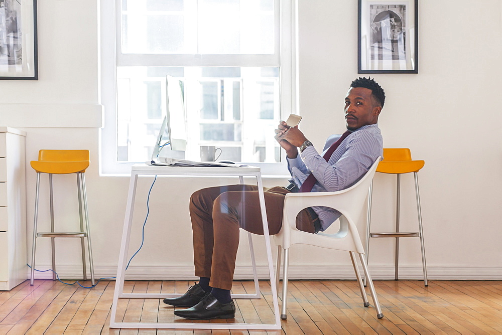 Serious Black businessman posing at computer desk