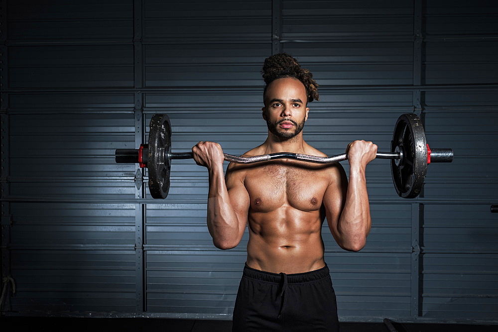 Mixed Race man lifting weights in gymnasium