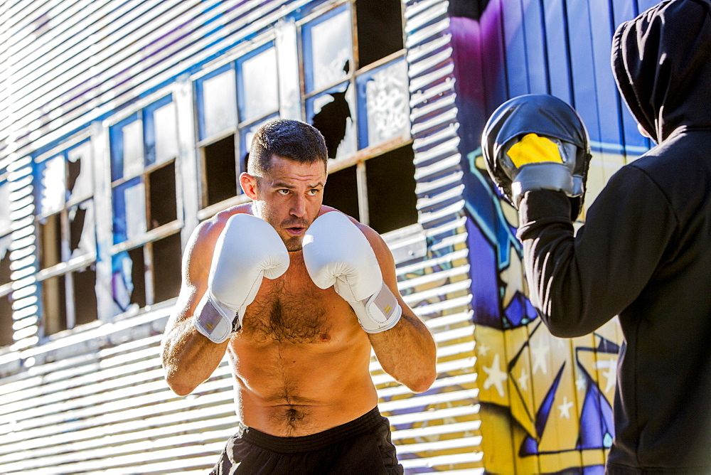 Caucasian boxer sparring with trainer