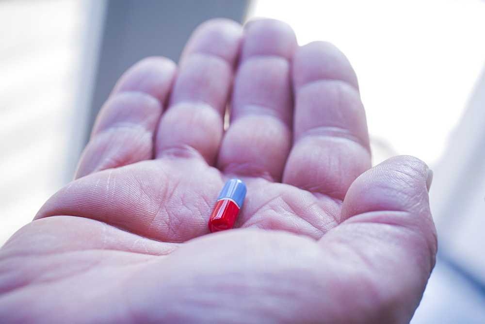 Hand of Hispanic man holding pill