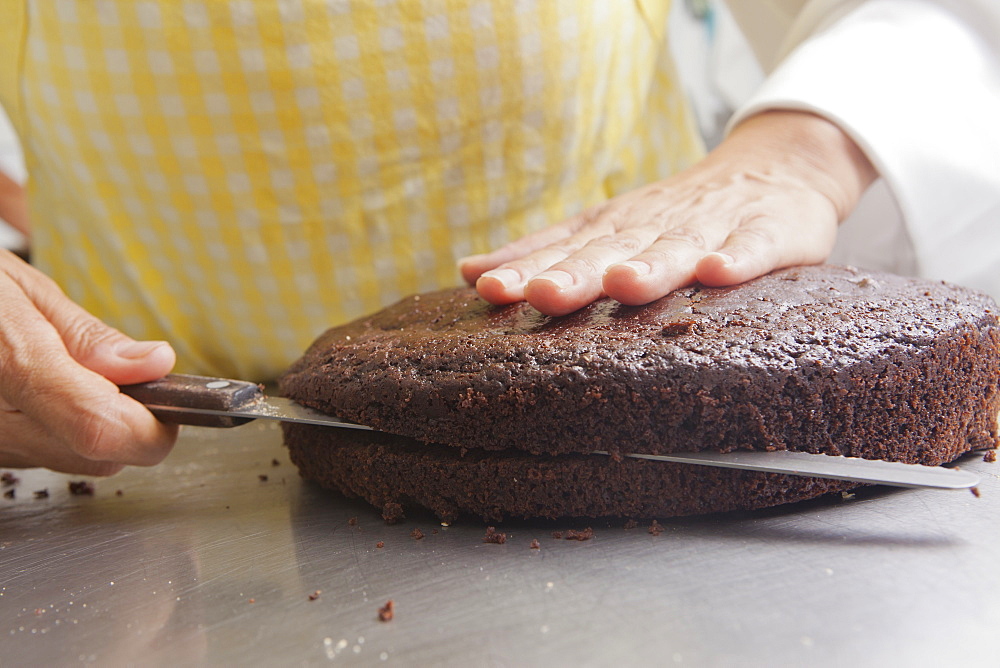 Hispanic woman cutting cake with knife