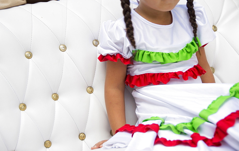 Girl with braids wearing festive dress on sofa