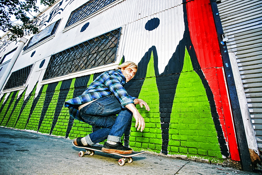 Caucasian man skateboarding on urban sidewalk