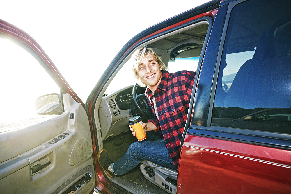 Caucasian man sitting in cat holding coffee cup