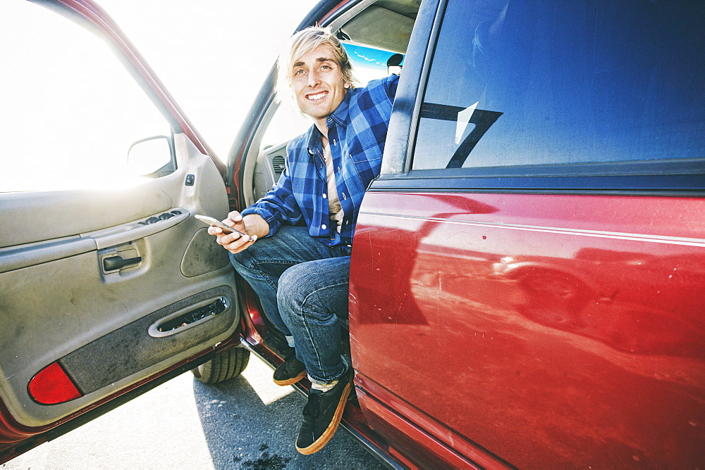 Caucasian man sitting in car texting on cell phone