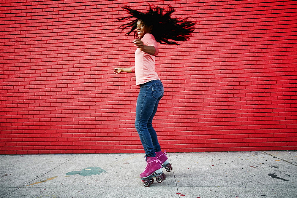 Black woman dancing on roller skates on sidewalk